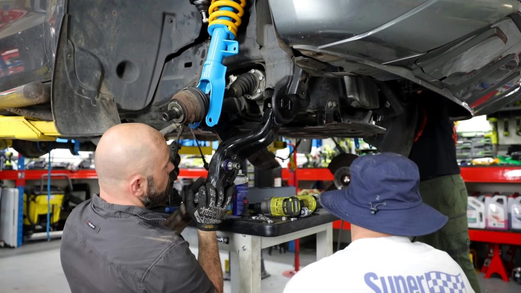 Two men working on a car in a garage